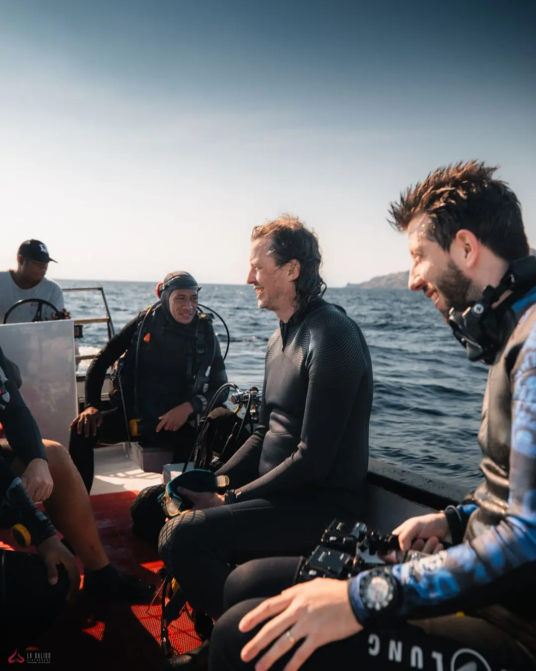 Group of scuba divers sharing smiles and laughter on La Galigo's dive deck after an exhilarating underwater adventure.