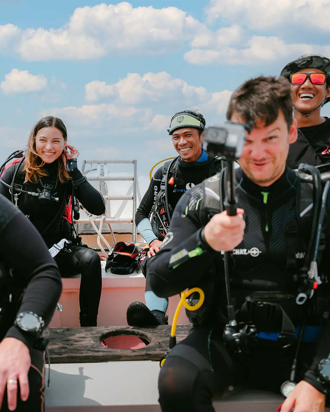 Joyful scuba divers sharing a laugh on La Galigo's speedboat amidst the stunning Indonesian seascape.