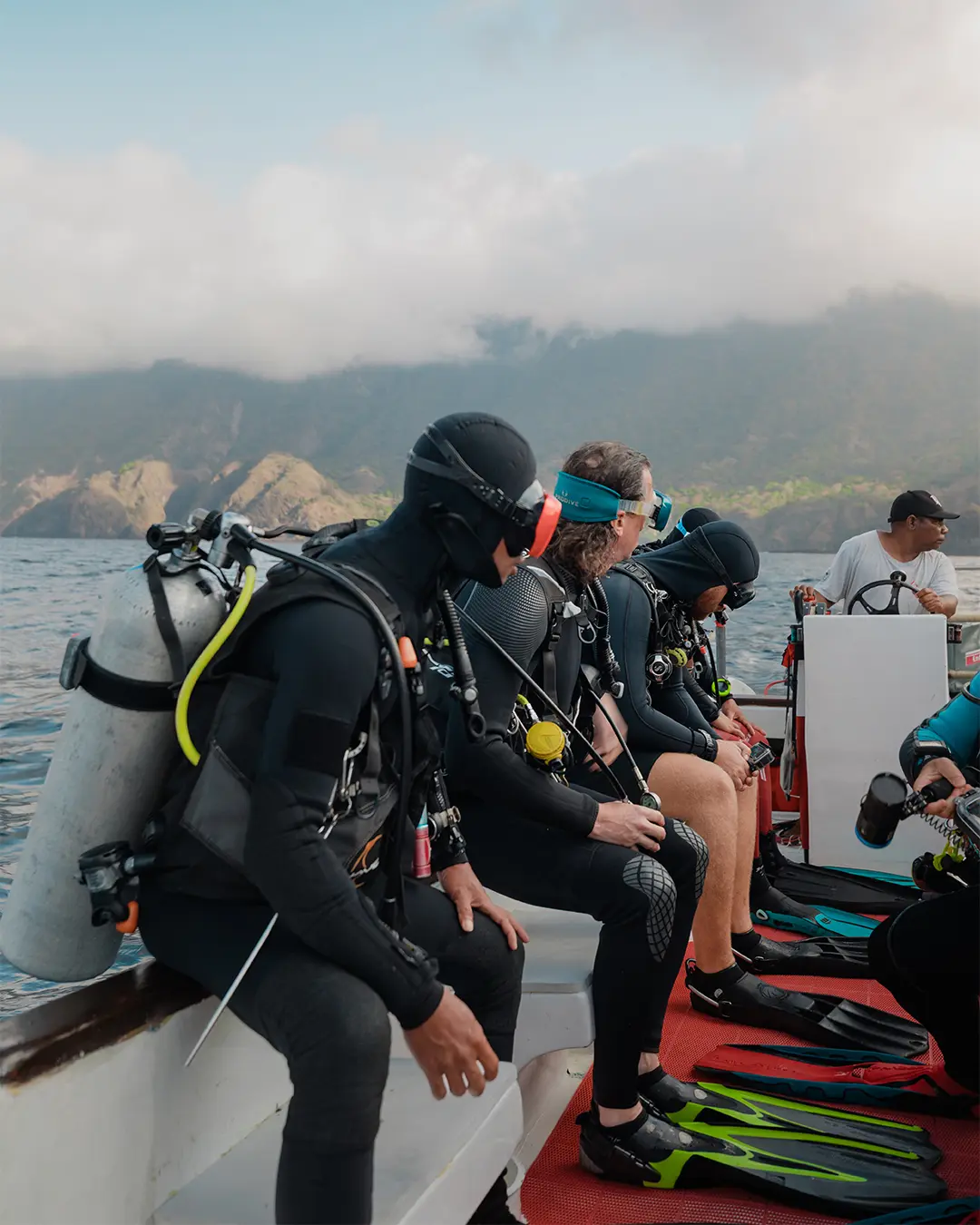 Scuba divers with La Galigo preparing for a backroll entry into the crystal-clear waters