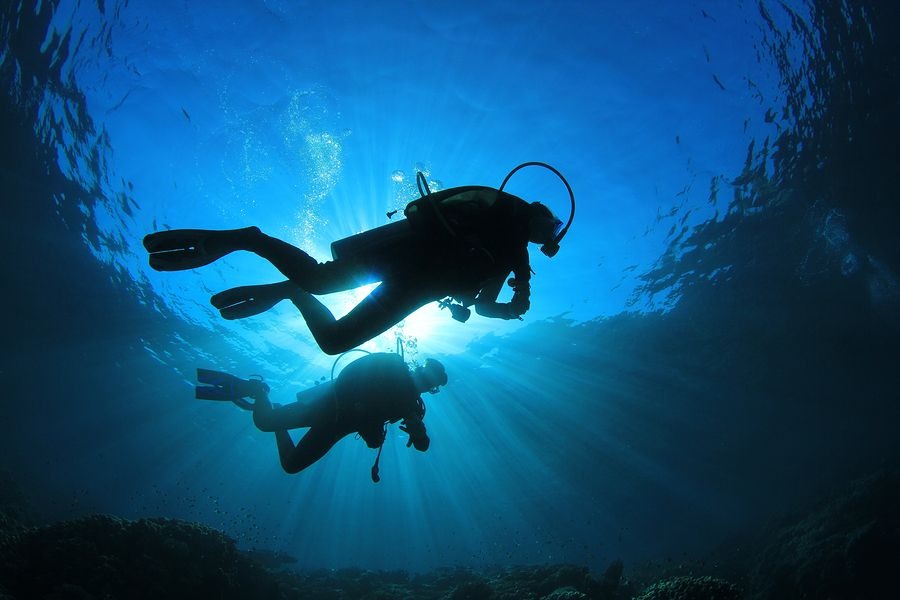 Two scuba divers equipped with Nitrox tanks exploring a coral reef, highlighting safe and efficient repetitive diving on a liveaboard